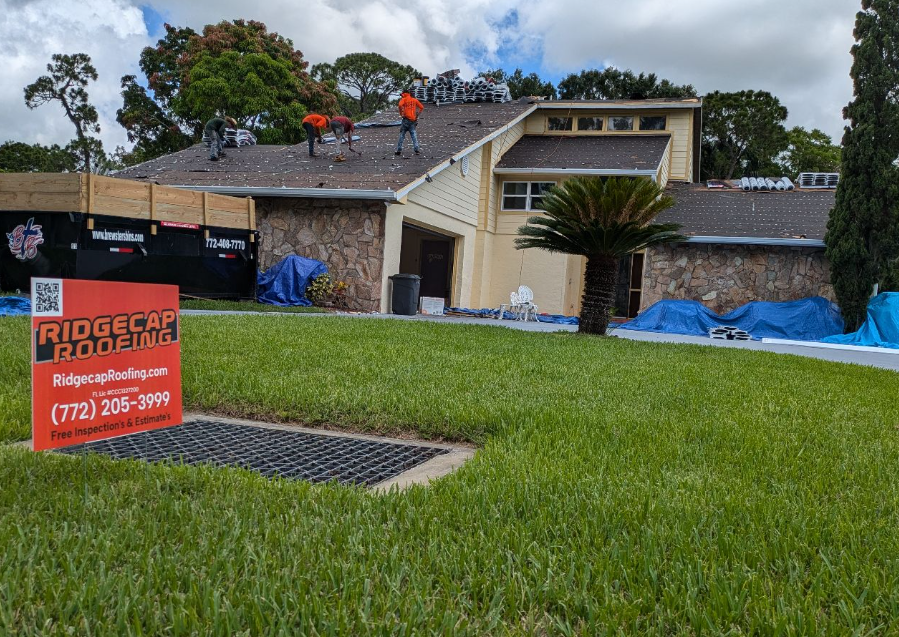 Ridgecap Roofing crew installing a new roof on a Florida home with a branded yard sign in front.