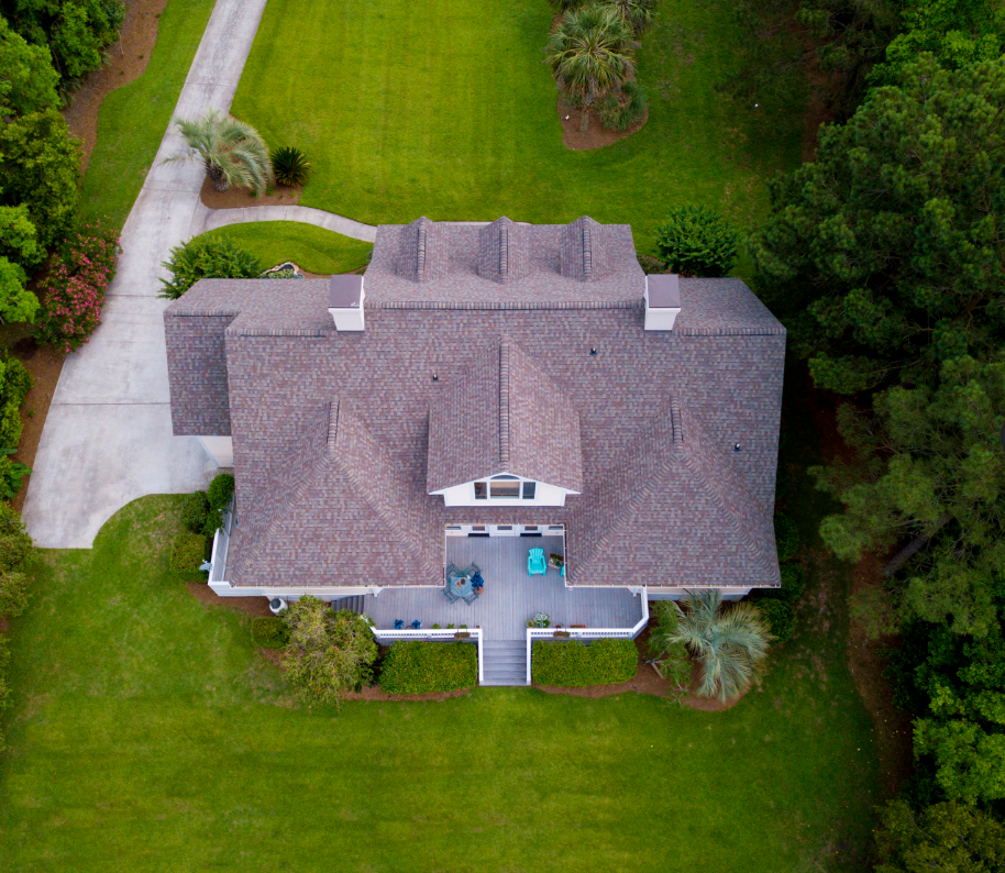 Aerial view of a completed brown shingle roof on a large residential home